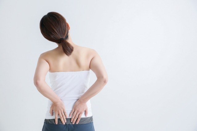 腰を抑える女性 写真